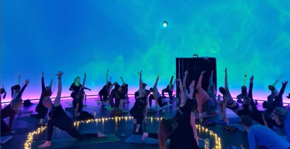 A photograph of people doing yoga in the Market Hall's immersive dome.